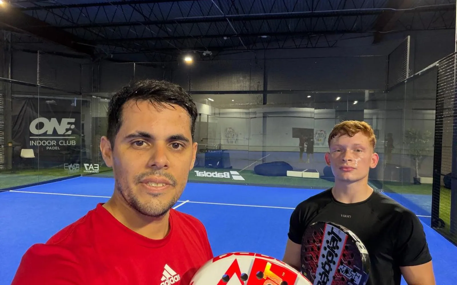 Emiliano Sosa with a student, each holding a padel racket, on the court at Padel Point
