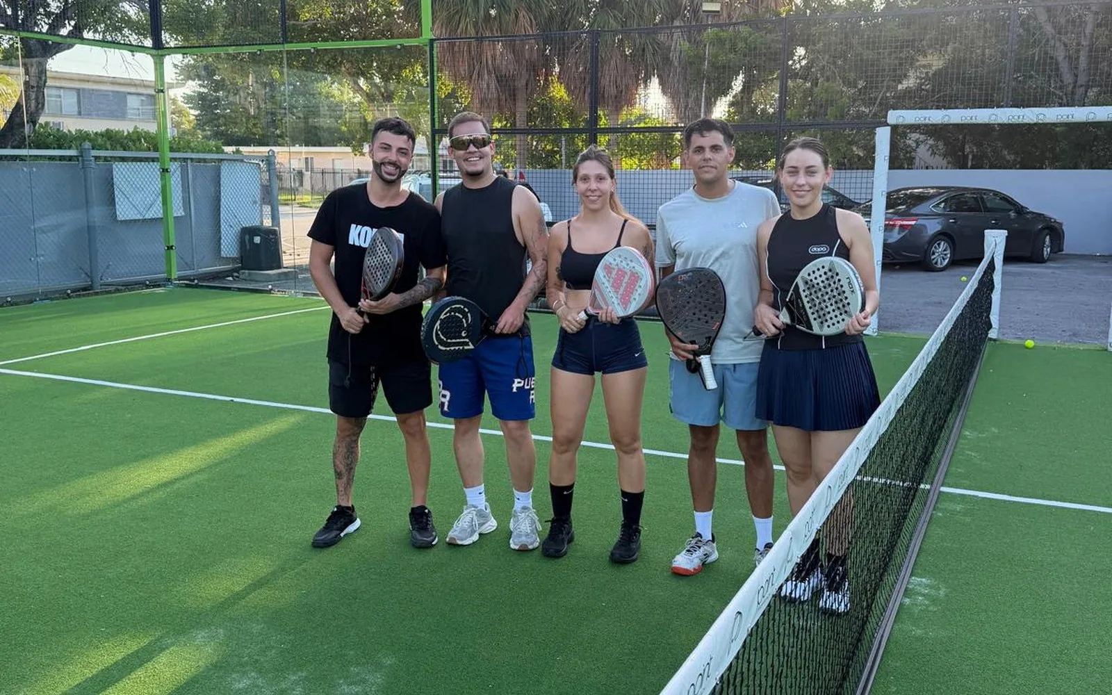 A group of adult students with their padel rackets on the court